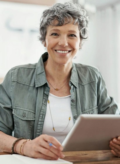 Lächelnde Frau mit Tablet in der einen Hand und Stift in der anderen