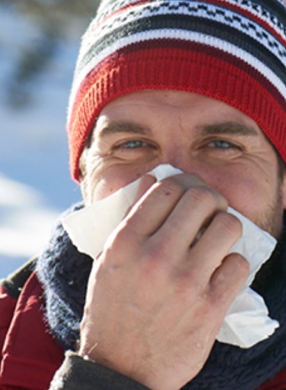 Mann putzt sich die Nase in winterlicher Landschaft 