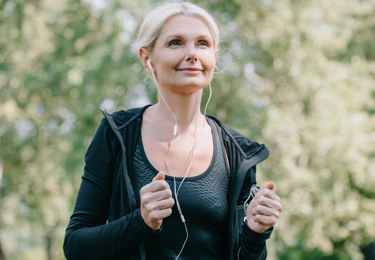 Une femme court dans le parc en écoutant de la musique