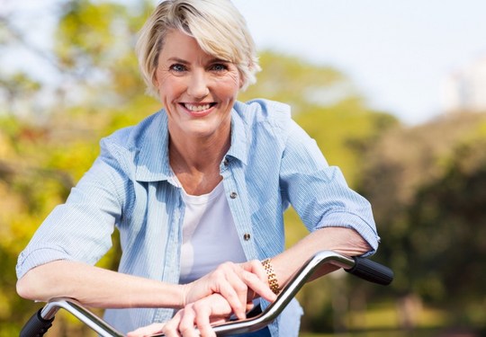 Lächelnde Frau auf dem Fahrrad im Park. 
